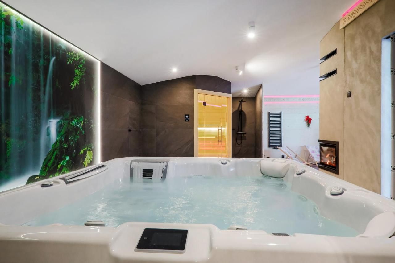 Duże jacuzzi, za nim sauna i prysznic, z boku kominek